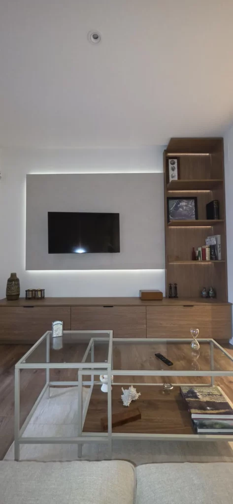 Salón reformado en León con mueble de TV a medida, estantería iluminada y panel retroiluminado