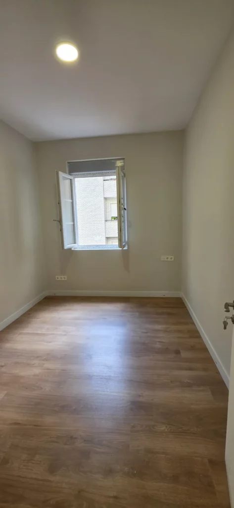 Habitación con puerta lacada blanca y plafón LED tras reforma integral de piso en León